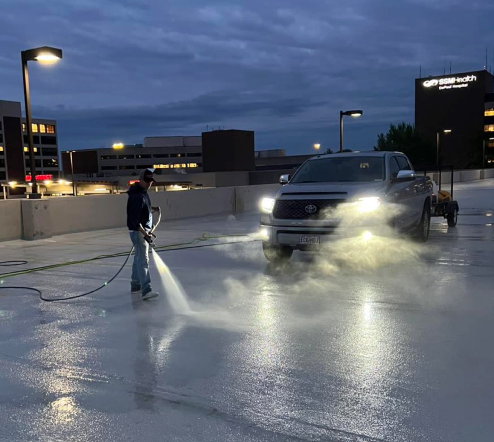 ATC crew pressure washing a hospital parking garage deck at night